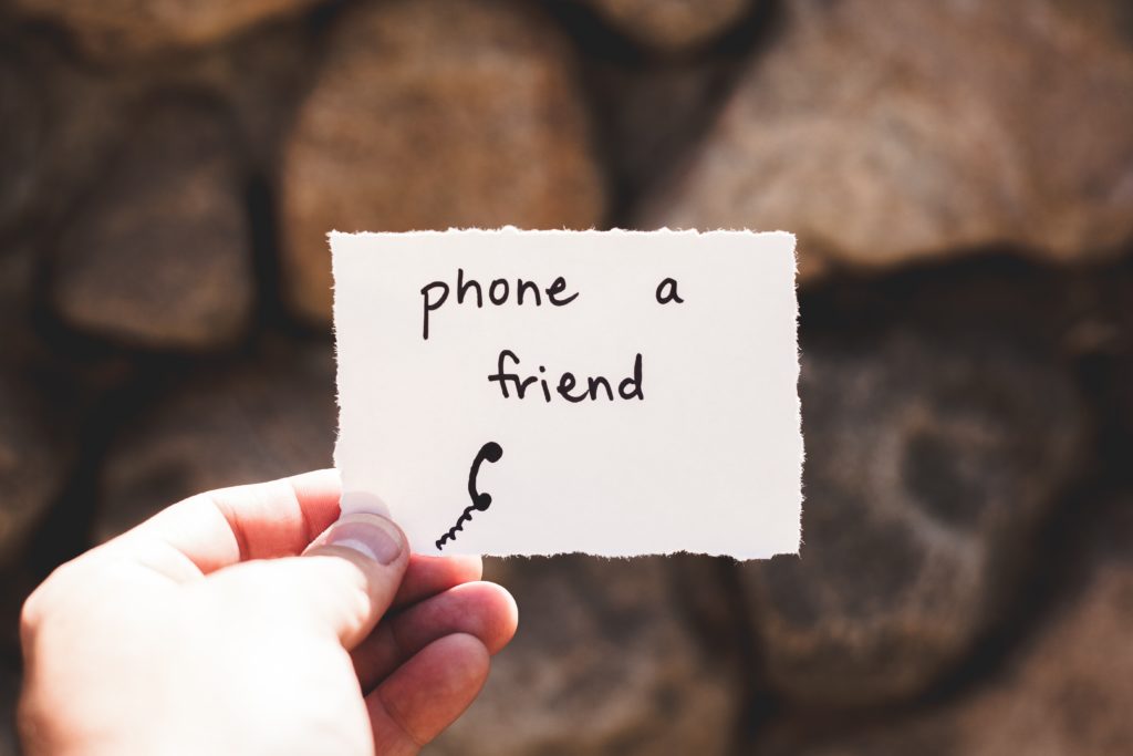 Hand holding paper that reads Phone a Friend